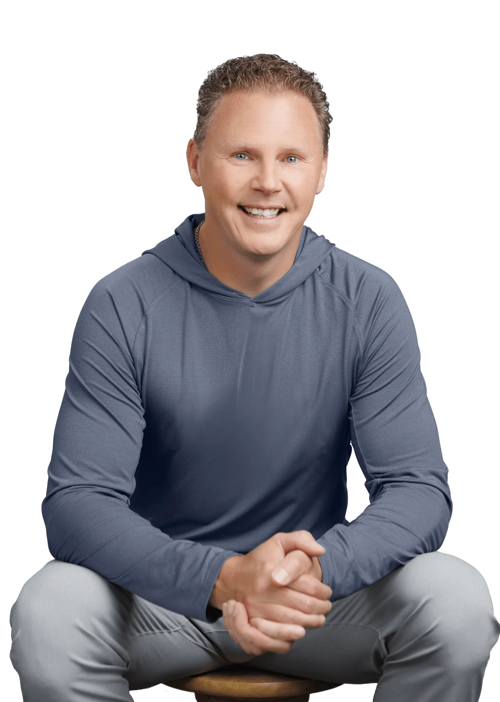 Chad Richardson seated on a stool, leaning forward with his hands clasped, smiling at the camera.